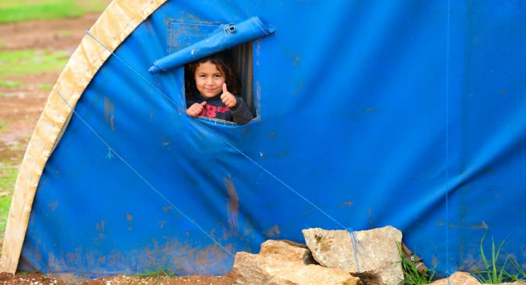 Small smiling girls looks out the window of a tent