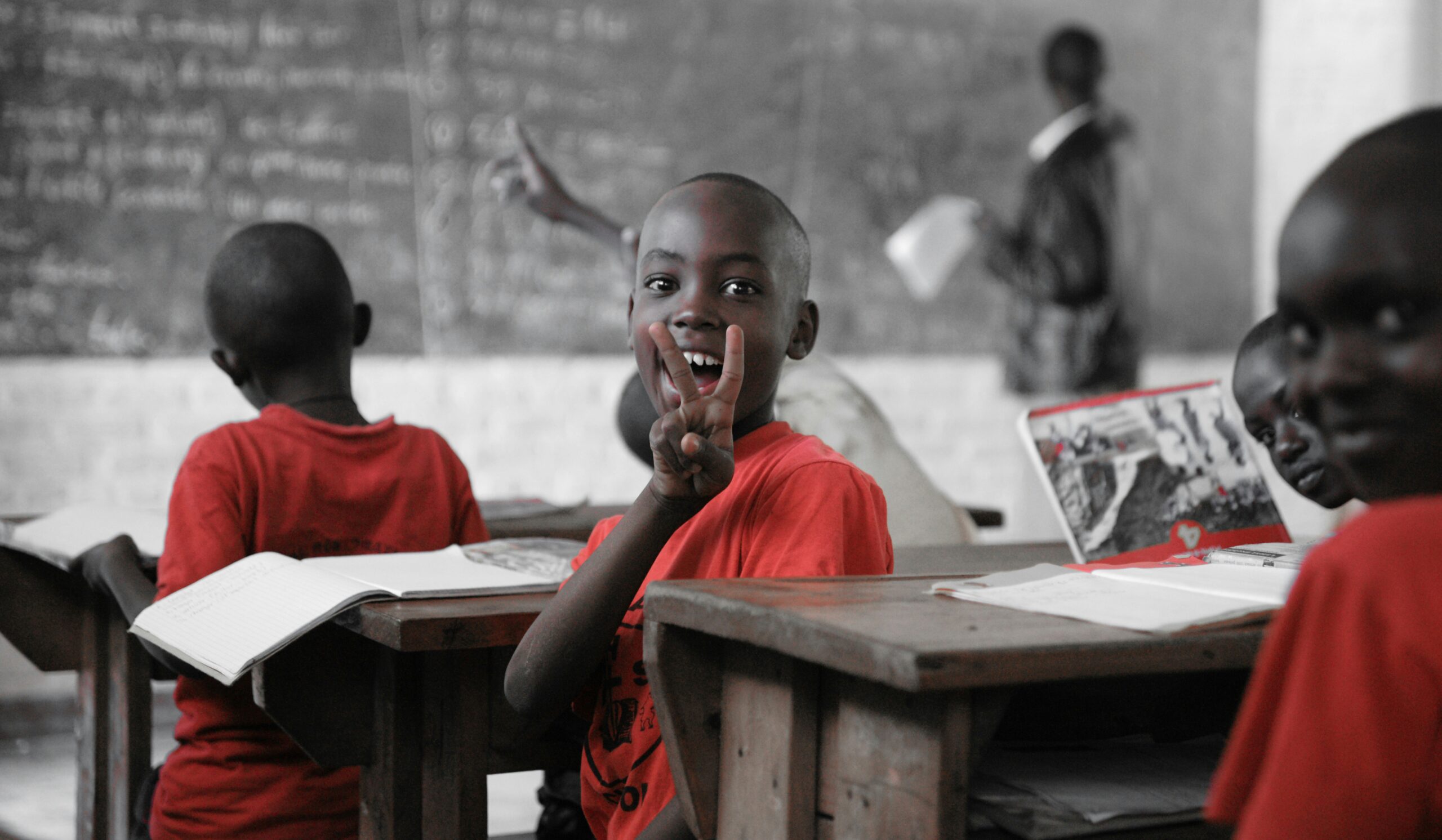 A young boy in a classroom turn away from the blackboard smiling